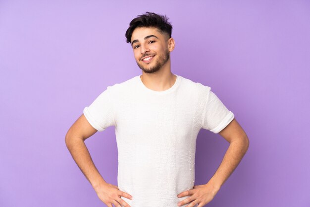 Arabian handsome man over isolated wall posing with arms at hip and smiling