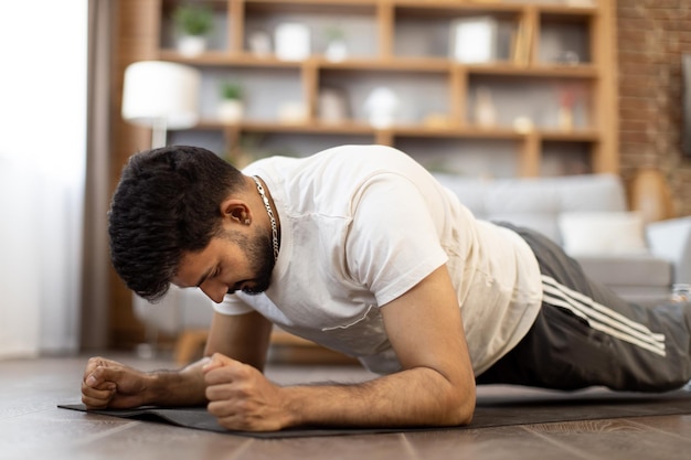 Arabian male athlete doing plank exercise at home