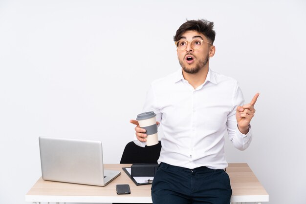 Arabian man in a office on white wall thinking an idea pointing the finger up