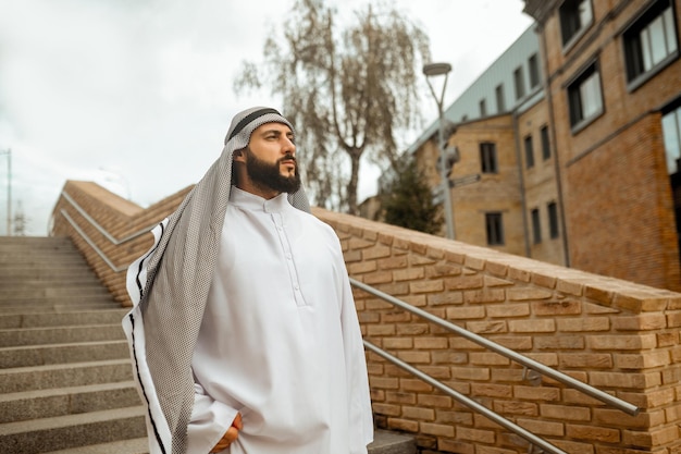 An arabian man in white traditional clothing on the stairs