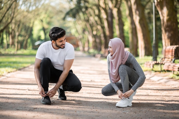 Arabian man and woman tying laces on sport sneakers