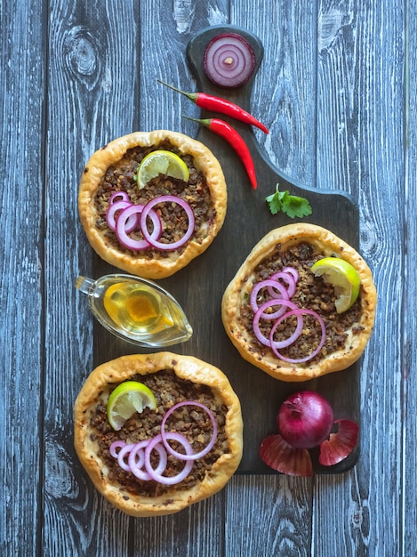 Arabian opened meat pies Sfiha on wooden cutting board.