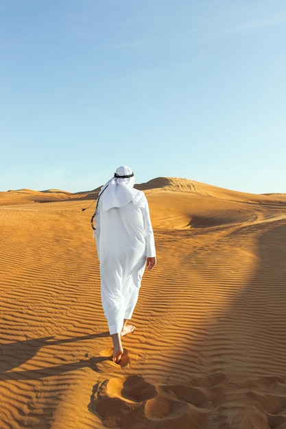 Arabian sheikh in long white dress closeup in the middle of Dubai desert