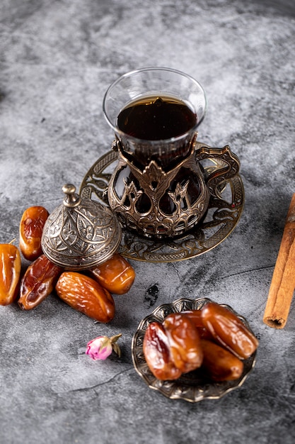 Arabic delight dates on a dark marble with a glass of tea
