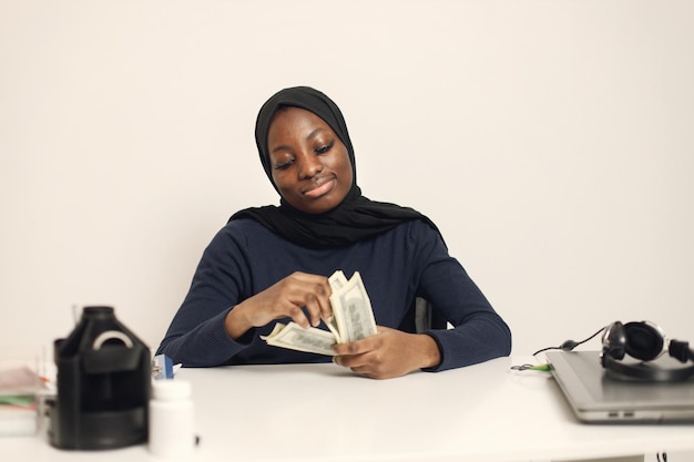 Arabic entrepreneur sitting in her office and holding cash