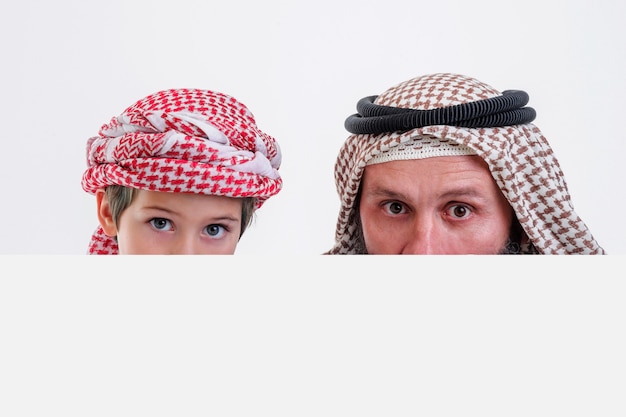 흰색 포스터를 들고 혀를 내밀고 있는 아들과 함께 아랍어 아버지 스톡 사진