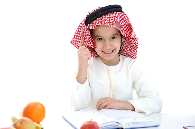 Arabic kid at school table with notebook and apple snack