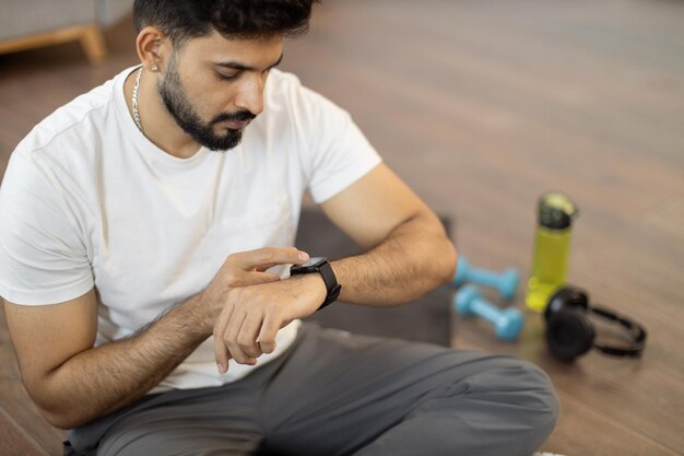 Photo arabic man setting heartrate watch during home training