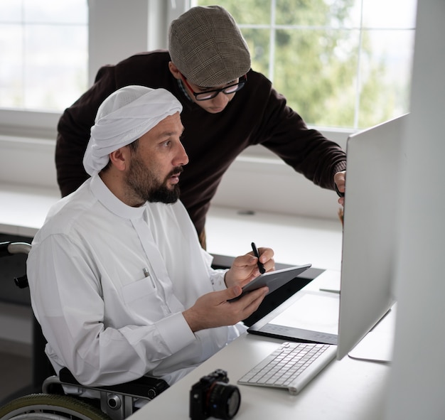 Arabic man in wheelchair at desk with computer