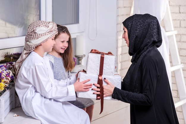 Arabic mother and kids posing with gift.Indoors.