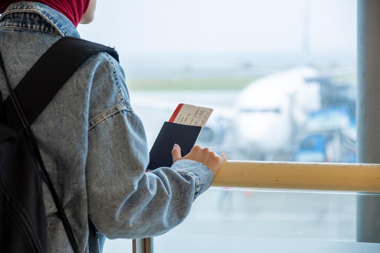 Photo arabic muslim female at the airport holding her passport and looking at airplane
