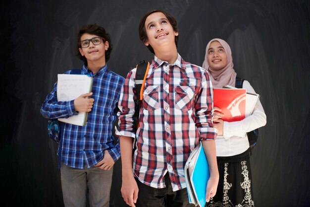 아랍어 십대, 학교에서 배낭과 책을 착용하는 검은 칠판에 대한 학생 그룹 초상화