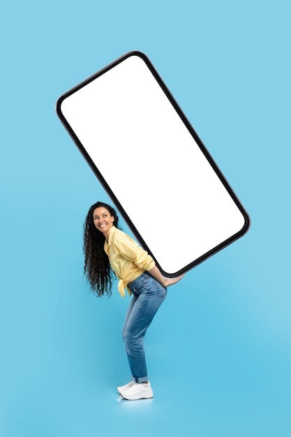 Arabic woman carrying big smartphone with empty screen blue background