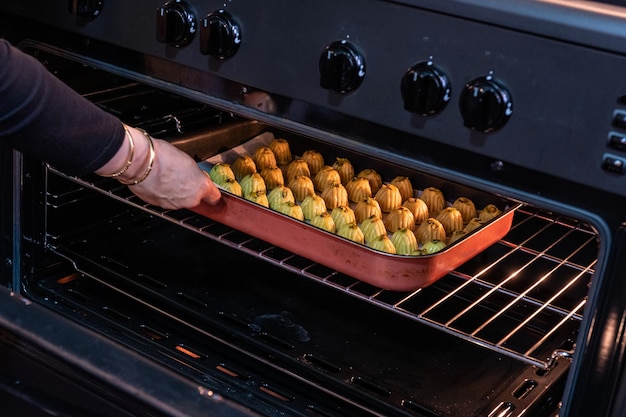 Arabic woman hand while putting Keto Eid kahk inside the oven