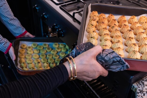 Arabic woman hand while putting Keto Eid kahk inside the oven