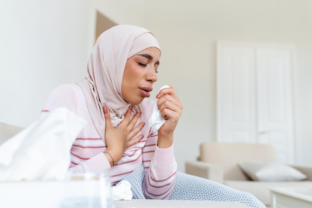 Arabic woman is having flu sick with a rhinitis womanwith hijab\
has dripping nose woman being sick having flu lying on sofa