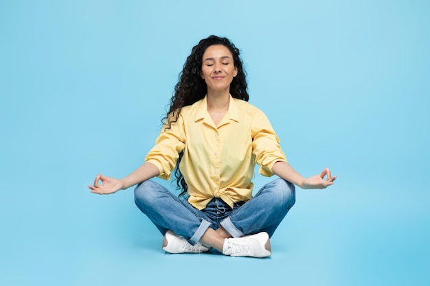 Arabic Woman Meditating Sitting In Lotus Position Over Blue Background