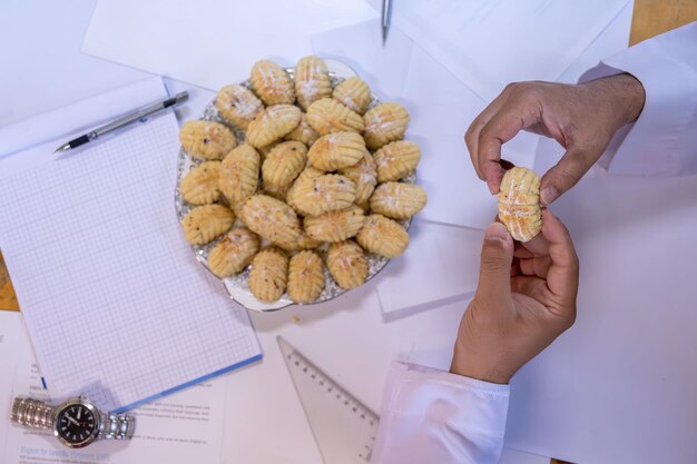 Arabic working colleagues hands eating eid kahk together on working desk