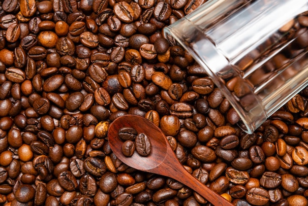 Foto chicchi di caffè arabica cucchiaio di legno e vetro trasparente su sfondo bianco