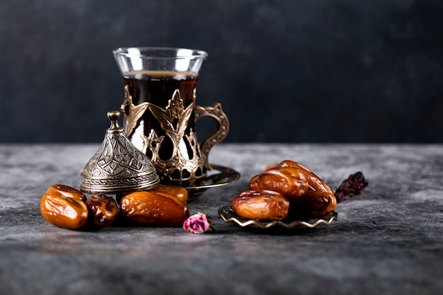 Arabisch genot dadels op een donker marmer met een glas thee op zwart