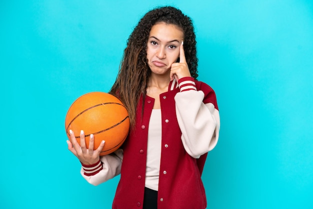 Arabische basketbalspelervrouw die op blauwe achtergrond wordt geïsoleerd die een idee denkt