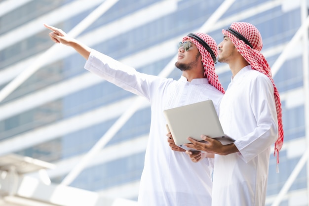 Arabische bedrijfsholdingslaptop die in stad werken