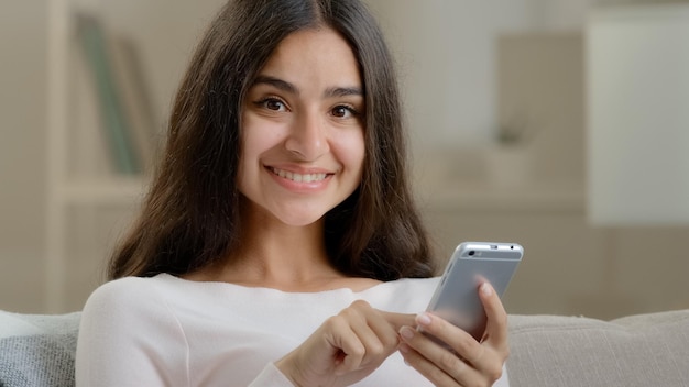 Arabische gelukkige vrouw brunette meisje jonge freelancer gebruiker scrolt mobiele interface klikkende smartphone