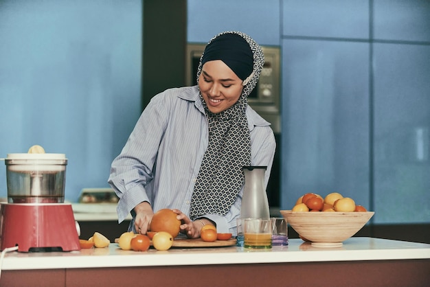 Arabische hijab-vrouw die vruchtensap maakt in de moderne keuken. Huisconcept. Gezond levensstijlconcept. Selectieve focus. Foto van hoge kwaliteit.