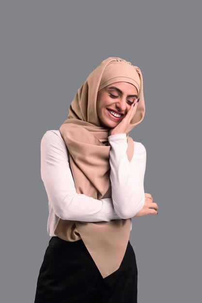 Foto arabische jonge vrouw in beige hijab die er gelukkig en tevreden uitziet