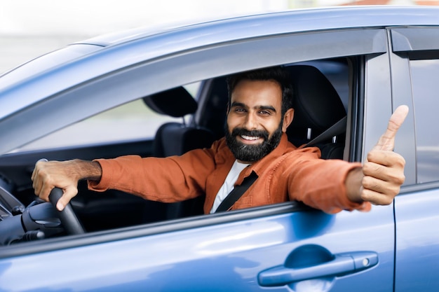 Arabische man die in de auto zit en zijn duim omhoog laat zien om het voertuig goed te keuren