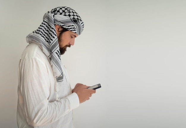 Arabische man die smartphone vasthoudt en naar het scherm kijkt Zijaanzichtportret met kopieerruimte