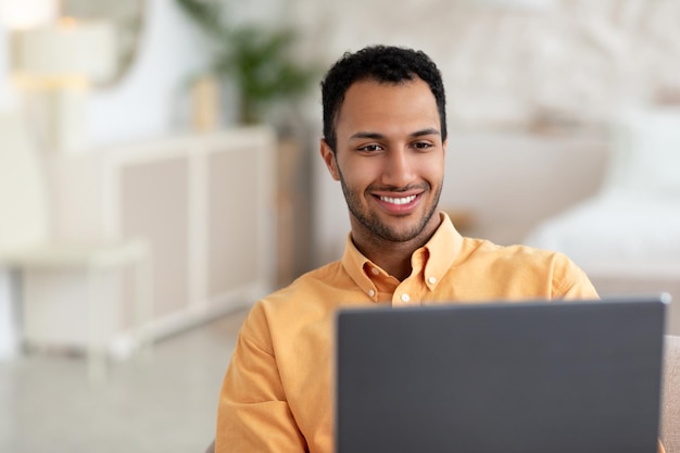 Arabische man met laptop die thuis op de bank zit