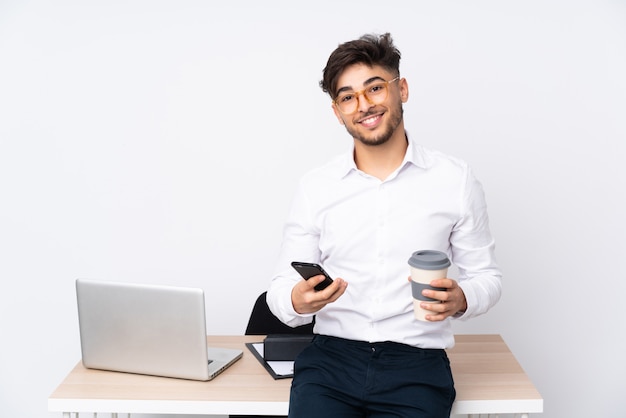 Arabische mens in een bureau op de witte weg te halen koffie van de muurholding en mobiel