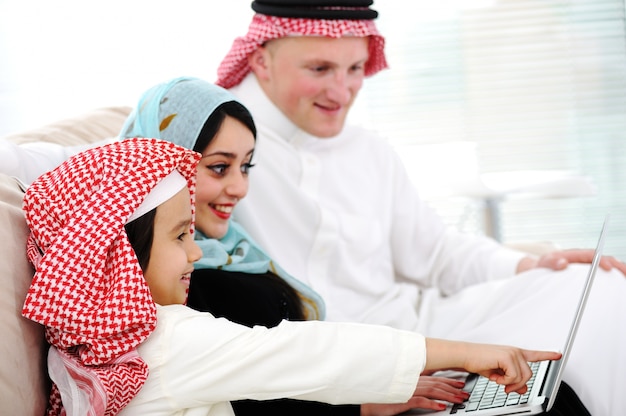 Foto arabische ouders en kleine jongen thuis met laptopcomputer