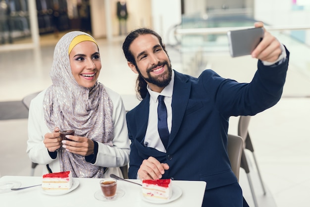 Foto arabische paar zitten in cafe en selfie maken.