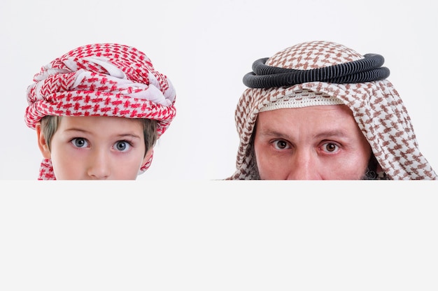 Arabische vader met zoon die een witte poster vasthoudt en zijn tong uitsteekt stock foto
