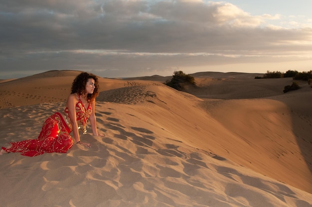 Arabische vrouw in de woestijnduinen bij zonsondergang