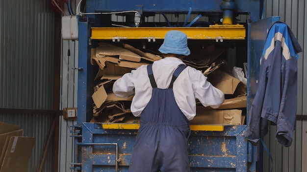 Arbeider bij het recyclen van karton bij industriële stortplaats, ecologieconcept, telefoto