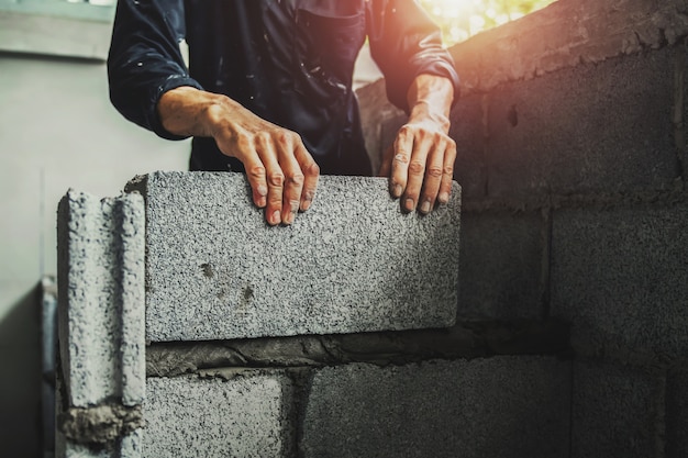 Arbeider bouwmuurbakstenen met cement