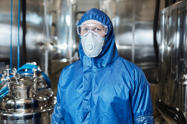 Arbeider die beschermende kleding draagt en naar de camera kijkt in een chemische fabriek