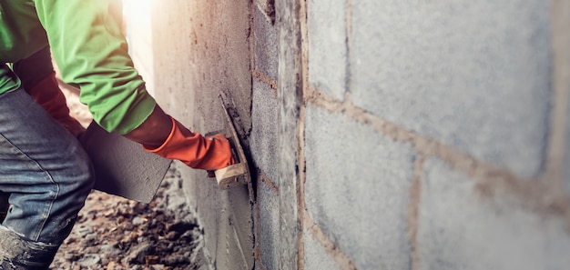 Arbeider die cement op muur pleisteren voor het bouwen van huis