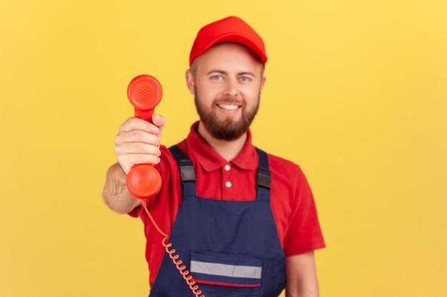 Arbeider die de handset vasthoudt en vraagt hem te bellen en service te bestellen die vriendelijk naar de camera kijkt