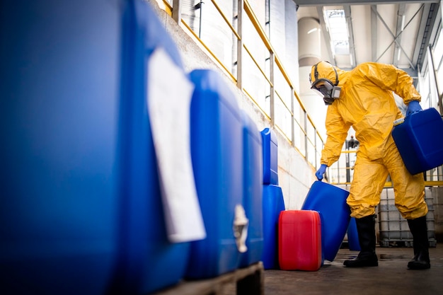 Arbeider die een beschermingspak en een gasmasker draagt en werkt in een fabriek voor de productie van chemicaliën