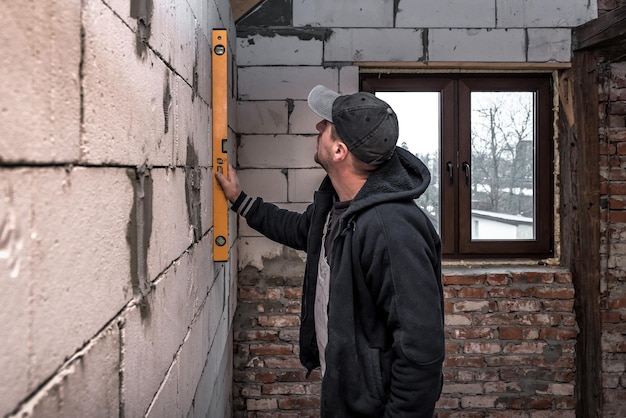 Arbeider die het niveau van de muur controleert met het waterpeilhulpmiddel