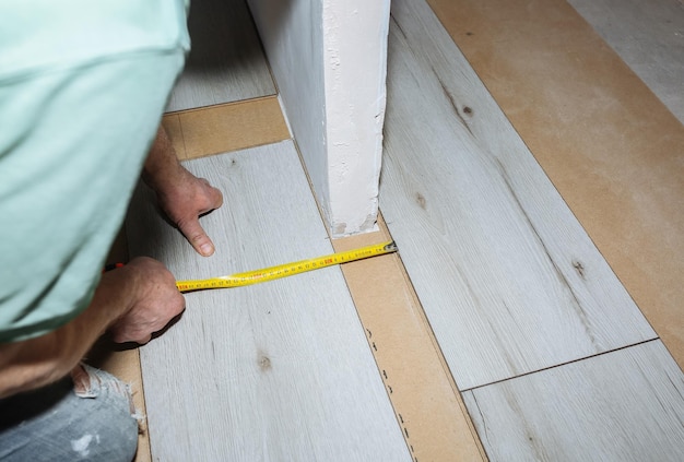 Arbeider die laminaatvloeren maakt in appartement Meet tape en potlood in handen Onderhoudsreparatie renovatie Houten parketplanken binnenshuis