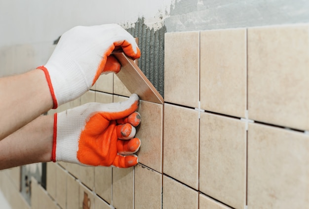 Arbeider die tegels op de muur in de keuken.