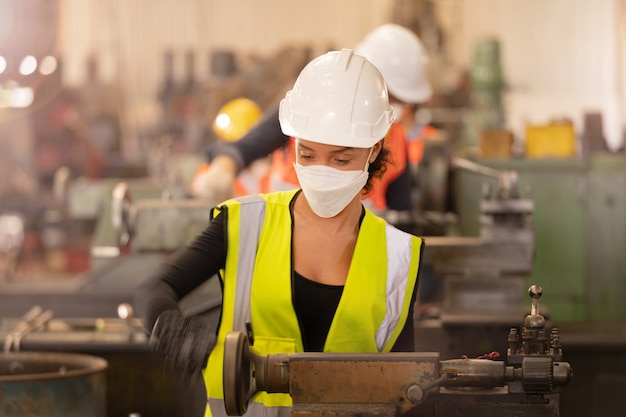 Arbeider Fabrieksmensen die gezichtsmasker en veiligheidspak dragen. vrouwen die in de fabriek werken.