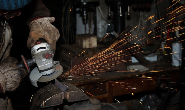 Arbeider in de zware industrie die staal snijdt met haakse slijper