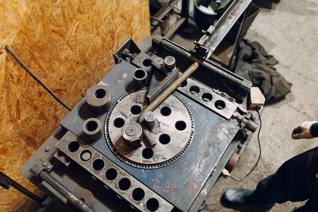 Arbeider in fabriek met industriële machine voor het buigen van metalen buizen