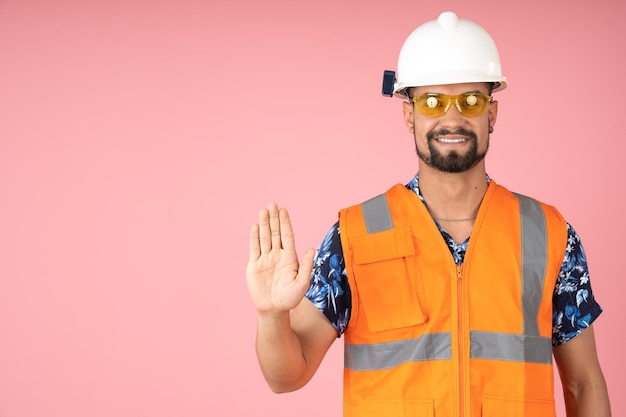 Arbeider met reflecterende vesthelm en veiligheidsbril die vraagt om met de hand te stoppen